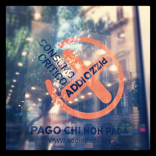An addiopizzo sticker on a the window of a Palermo business.
