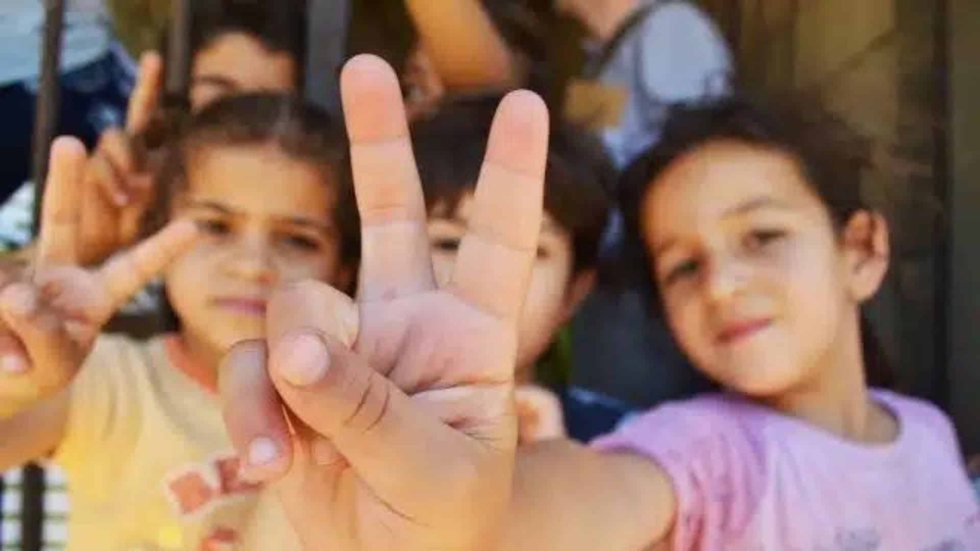 Syrian refugee children in Lebanon make the peace sign.