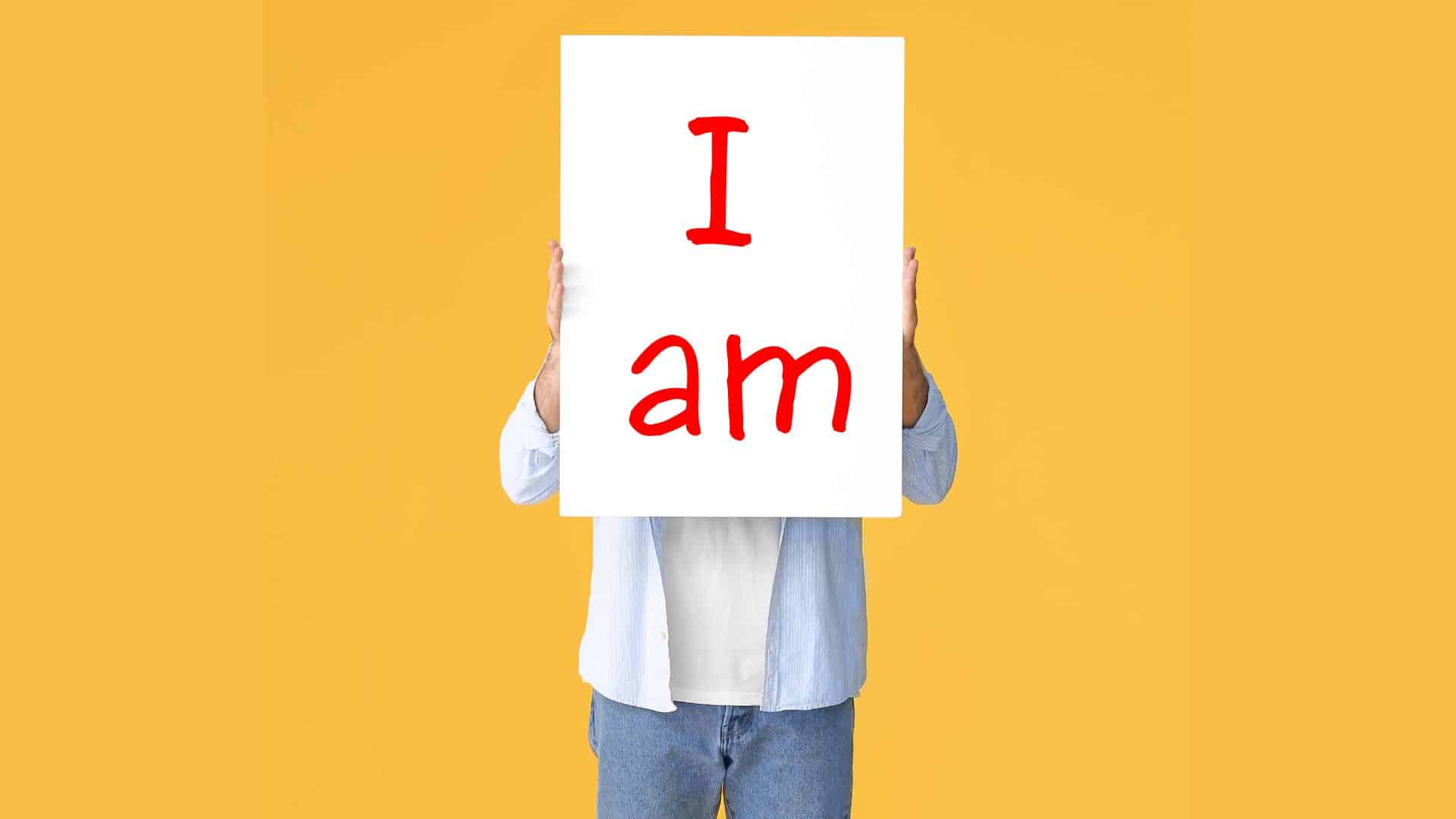 A man holds a sign that says I am.