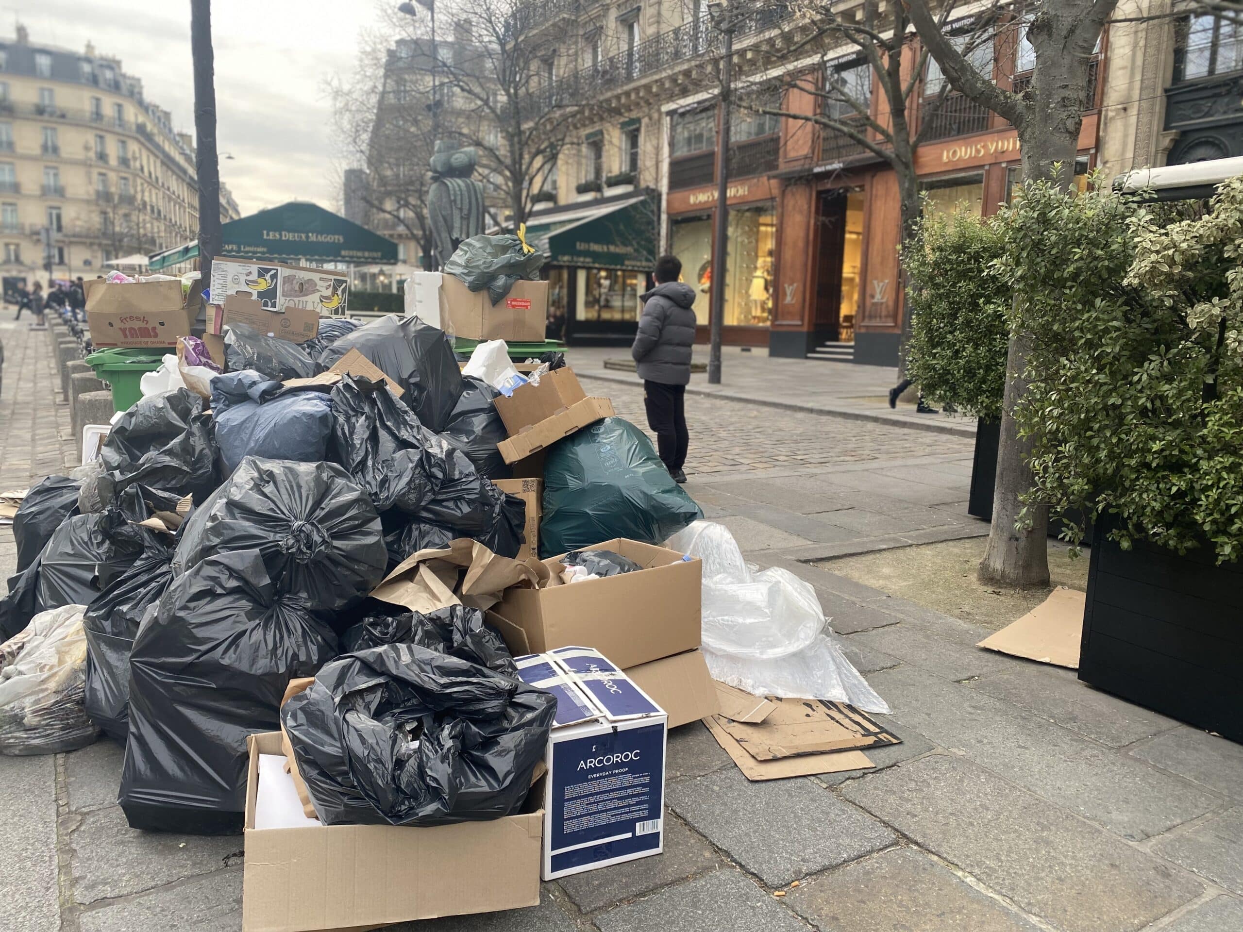 Piles of trash in front of a Louis Vuitton luxury store.