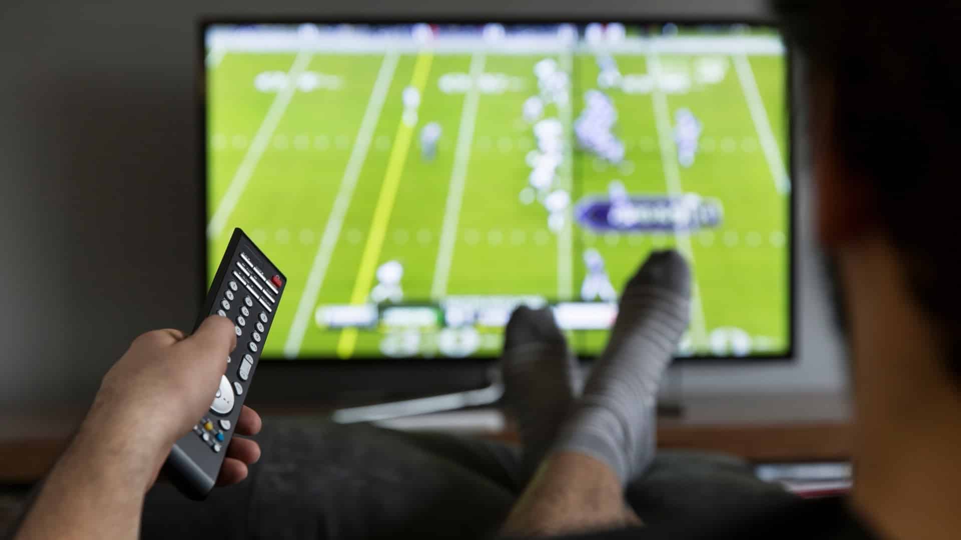 A man watches a football game on television.