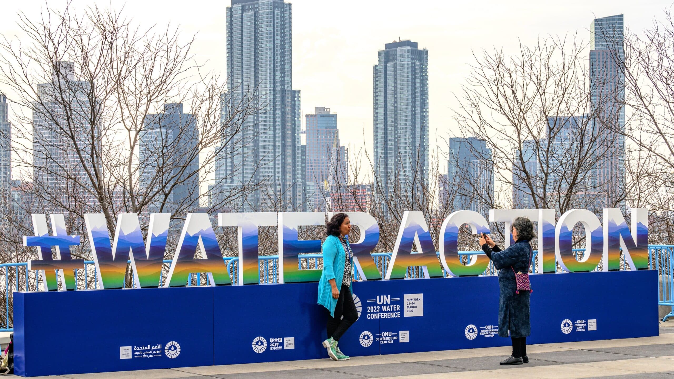 Delegates to the United Nations 2023 Water Conference take photos in front of a display set up at the entrance of the UN headquarters.