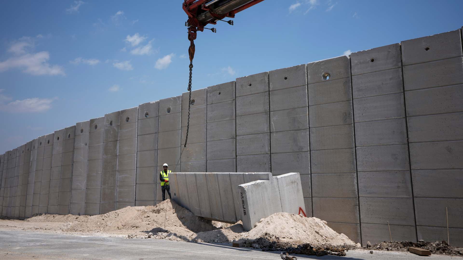 Workers place sections of a nine-meter (30-foot) high concrete wall to replace a border fence between the northern West Bank and Israel