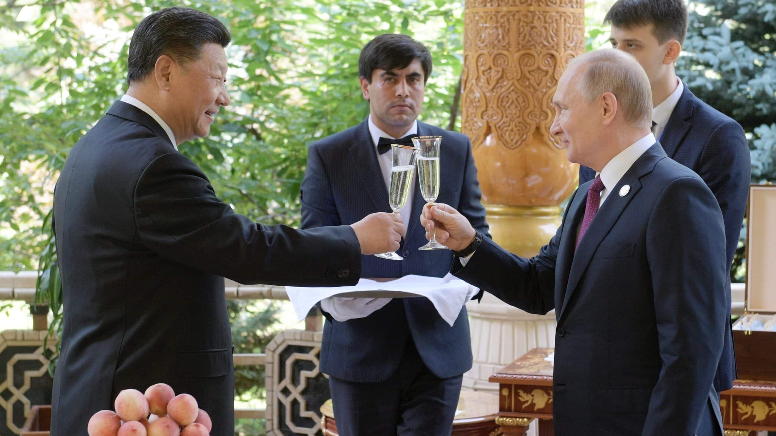 Vladimir Putin and Xi Jinping click champagne glasses at a dinner.